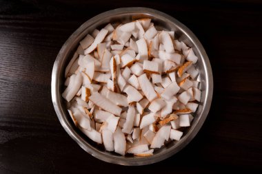 Taze hindistan cevizi parçaları koyu ahşap masada kasede.