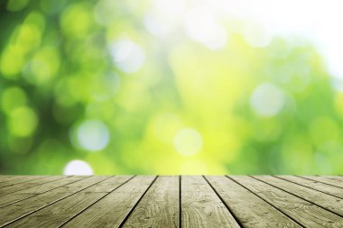 Ahşap masa ve bulanık yeşil bokeh doğa arka planı.