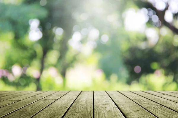 Ahşap masa ve bulanık yeşil bahçe arka planı.