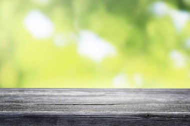 Bulanık yeşil bokeh ve ahşap masa arkaplanı.
