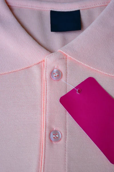 Light orange polo t-shirt and pink tag label.