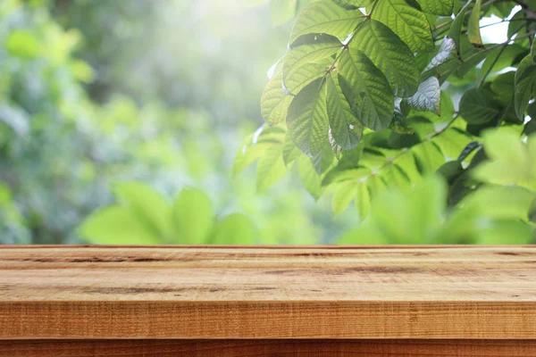Güzel güneş ışığı bulanık yeşil bahçe arka planı ve ahşap masa..