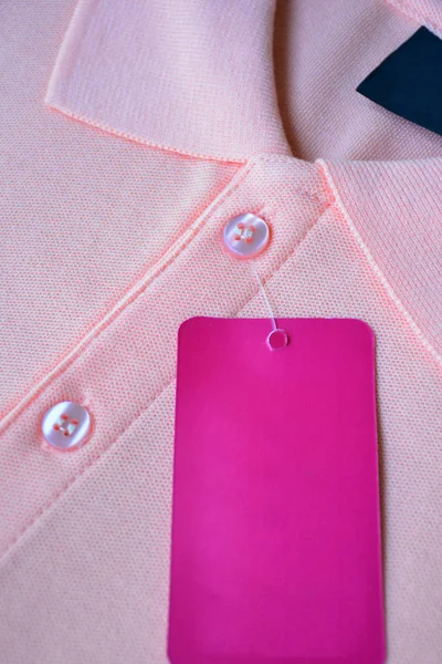 Light orange polo t-shirt and pink tag label.