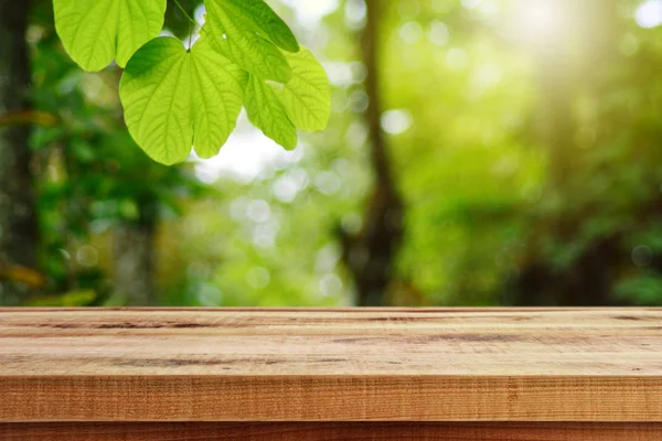 Ahşap masa ve bulanık yeşil yaprak arka planda.. 