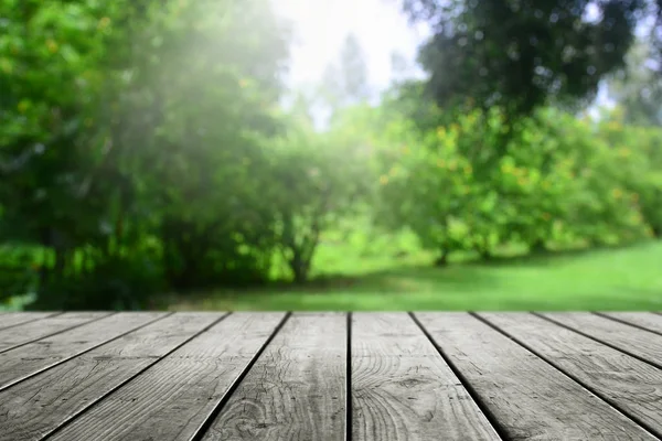 Boş ahşap masa ve bulanık bahçe arka planı. 