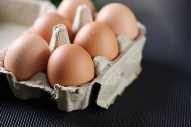 Siyah arka plandaki karton kutuda taze tavuk yumurtası..