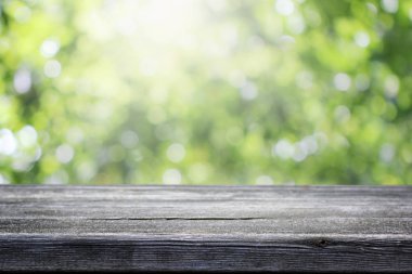 Bulanık yeşil bokeh ve ahşap masa arkaplanı.