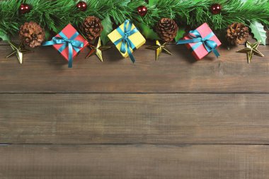 Sınırlı ahşap arka plan yeşil yaprak, çam kozalakları, altın yıldızlar, kırmızı toplar ve hediye kutuları. Noel konsepti.