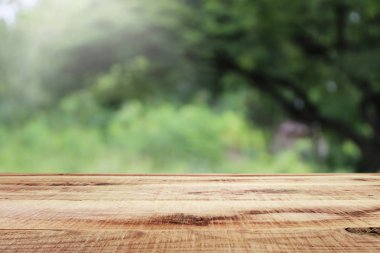 Bulanık yeşil bahçe ve ahşap masa arkaplanı..