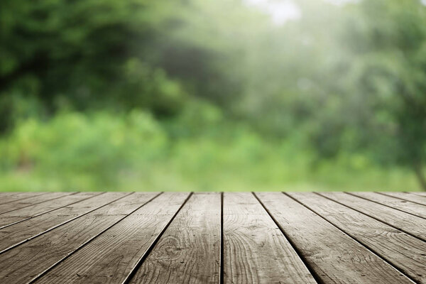 Blurred abstract green bokeh of garden and wooden table background.