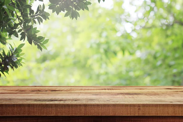 木製の机と庭の背景にぼやけた緑の性質 — ストック写真