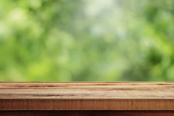 Bulanık yeşil ve ahşap masa arkaplanı.