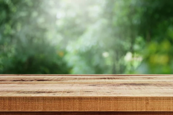Bulanık yeşil bahçe ve ahşap masa arkaplanı..