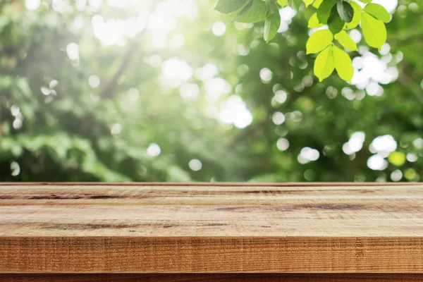 木製のテーブルとぼやけた緑の葉自然のボケの背景 — ストック写真