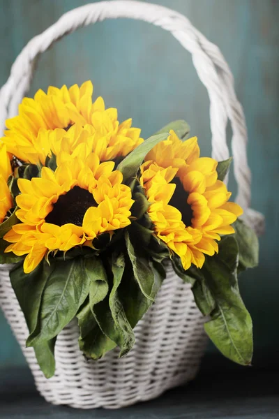 Beautiful sunflowers in white basket on the table. Autumn background.