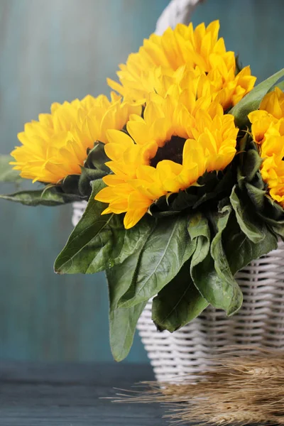 Beautiful sunflowers in white basket on the table. Autumn background.