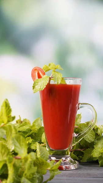 Fresh tomato juice with tomatoes and peppermint leave on table, Healthy food.