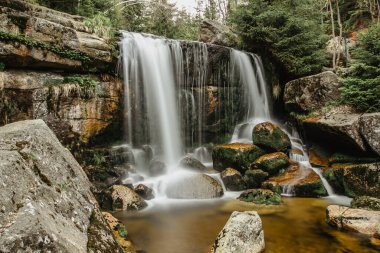 Waterfall photo. Long exposure photo of a beautiful Jedlova waterfall, Jizerske mountains, Czechia. Motion blurr water in a mountain creek in deep forest. Hiking in a nature reserve.Fresh clean water clipart
