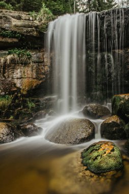 Şelale fotoğrafı. Güzel bir Jedlova şelalesinin uzun pozlama fotoğrafı, Jizerske dağları, Çek. Ormanın derinliklerindeki bir dağ deresinde hareket bulanık su. Doğa koruma alanında yürüyüş. Temiz su.