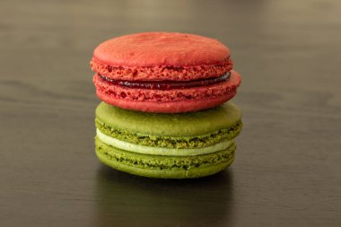 Tatlı ahududular ve şam fıstıklı kurabiyeler koyu ahşap arka planda izole edilmiş. Fransız pastası. Küçük lezzetli Fransız pastaları. Geleneksel Fransız tatlıları. Yakın plan.