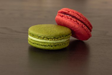 Tatlı ahududular ve şam fıstıklı kurabiyeler koyu ahşap arka planda izole edilmiş. Fransız pastası. Küçük lezzetli Fransız pastaları. Geleneksel Fransız tatlıları. Yakın plan.