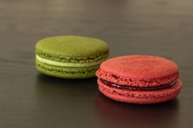 Tatlı ahududular ve şam fıstıklı kurabiyeler koyu ahşap arka planda izole edilmiş. Fransız pastası. Küçük lezzetli Fransız pastaları. Geleneksel Fransız tatlıları. Yakın plan.