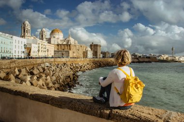 Sırt çantalı mutlu bayan gezgin, Cadiz, Endülüs, İspanya 'da güneşli bir günde eski şehir ve Santa Cruz Katedrali' nin deniz manzarasının keyfini çıkarıyor. Avrupa şehir manzarası..