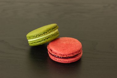 Tatlı ahududular ve şam fıstıklı kurabiyeler koyu ahşap arka planda izole edilmiş. Fransız pastası. Küçük lezzetli Fransız pastaları. Geleneksel Fransız tatlıları. Yakın plan.