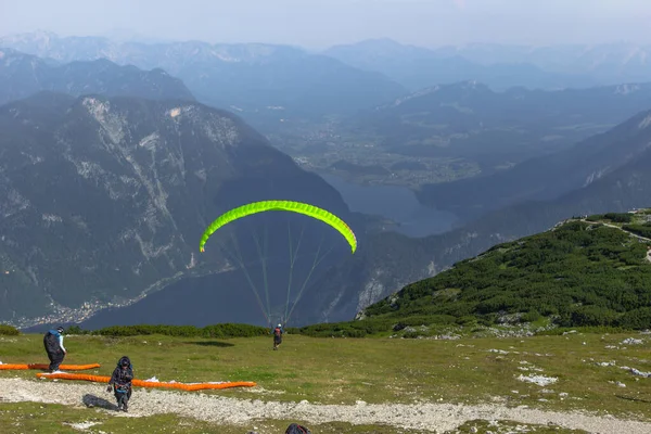 A paraglider at the start of the Krippenstein mountain in the Dachstein area,Austria.Paraglide silhouette over Hallstatter See.Extreme adrenaline sport.Wild free atmosphere.Person in the air. — Stock Photo, Image