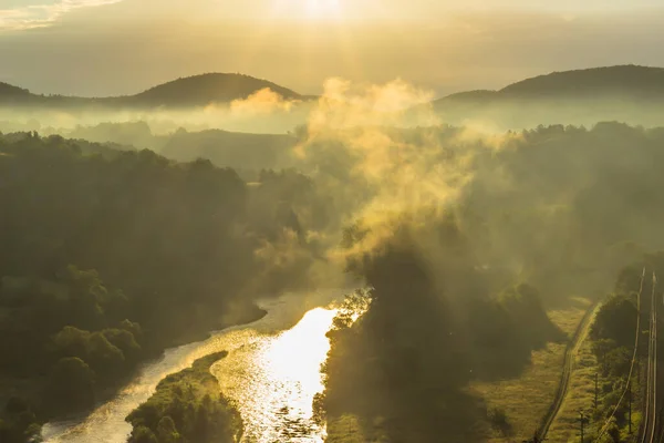 Panoramic view of a river and misty forest. Foggy morning outdoors.Misty forest scenery.Colorful summer morning with golden sunlight.Fantastic foggy sunrise.Beautiful sun rays with clouds.Hills in fog