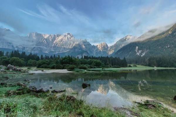 Spiegelreflectie in Lago di Fusine, Italië. Zomer lente kleuren en Mangart berg op de achtergrond bij zonsopgang in Italien Alpen.Prachtige rustige natuur, turquoise water, reizen achtergrond — Stockfoto