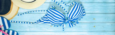Web pankartı ve düz bir yaz mevsimi mayolu ve plaj aksesuarlı mavi ahşap arka planda