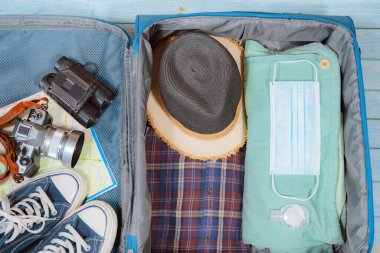 Koruyucu maskeli ve aksesuarlı üst görünüm yeni normal tarzda seyahat için bagajda hazır olsun.