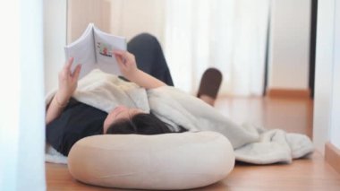 Asyalı kadınla sağlık ve refah kavramı uzan ve oturma odasında kitap oku.