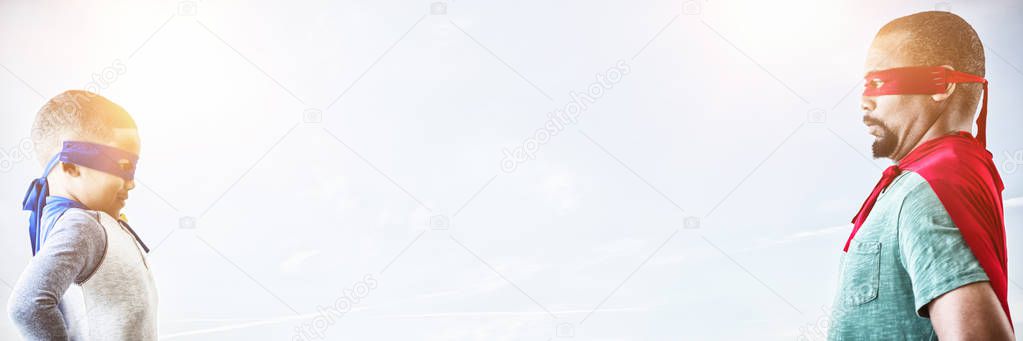 Father and son pretending to be superhero against blue sky with white clouds