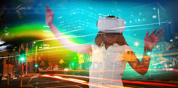 Girl enjoying while wearing virtual reality simulator against illuminated roads by building in city