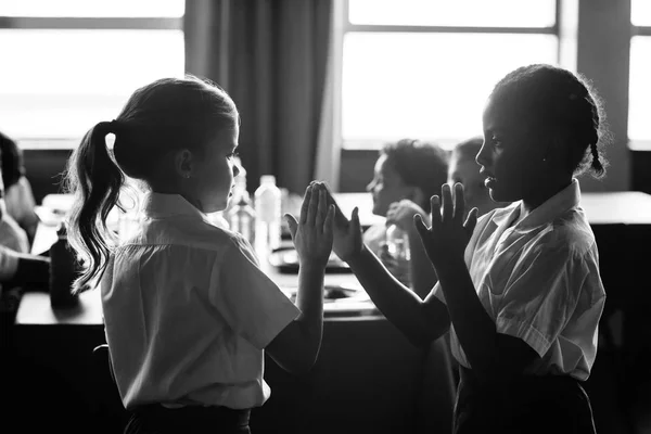 Schoolgirls playing clapping game in canteen