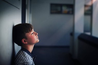 Üzgün okul çocuğu eğilimli baş okulun koridorda duvara yakın çekim