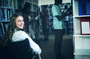 Tekerlekli sandalyede okul kütüphanesinde Engelli kız portresi