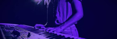 Mid section of female musician playing piano in illuminated nightclub clipart