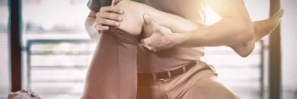 クリニックの女性に膝の治療を与える理学療法士 — ストック写真