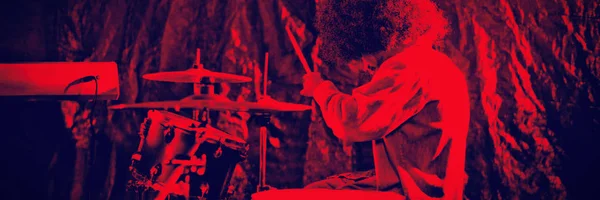 男鼓手的侧面视图与非洲头发演奏鼓套件在夜总会 — 图库照片