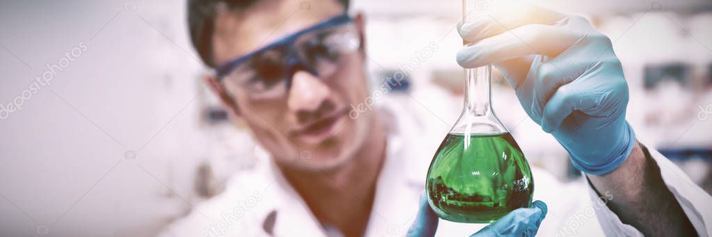 Chemist holding up beaker of green chemical in the laboratory