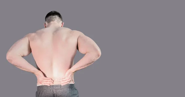 Digital composite of Man holding back pain with blank grey background
