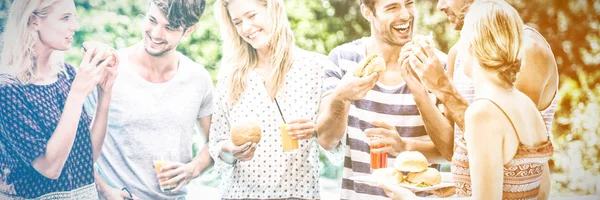 Group of friends having hamburgers and juice at barbecue party