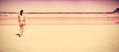 Kumsalda güneşli gün boyunca yürüyüş kadın arkadan görünüş