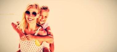 Mutlu anne kızı plajda güneşli gün boyunca piggybacking