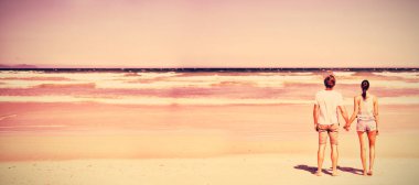 Arkadan görünüş güneşli gün boyunca sahilde elele Çift