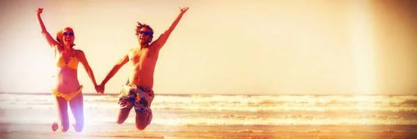 Allegro Coppia Che Tiene Mano Mentre Salta Spiaggia Contro Cielo — Foto Stock