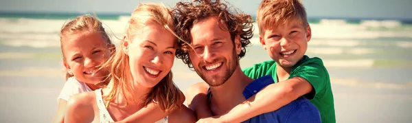 日当たりの良い日中にビーチで便乗幸せな家族の肖像画 — ストック写真